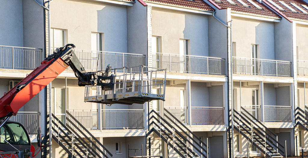 Module d'extension en bois suspendu par une grue au-dessus d'un jardin résidentiel